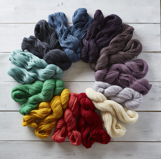 Rainbow of skeins of Kelbourne Woolens Andorra on a wide plank white painted wooden floor